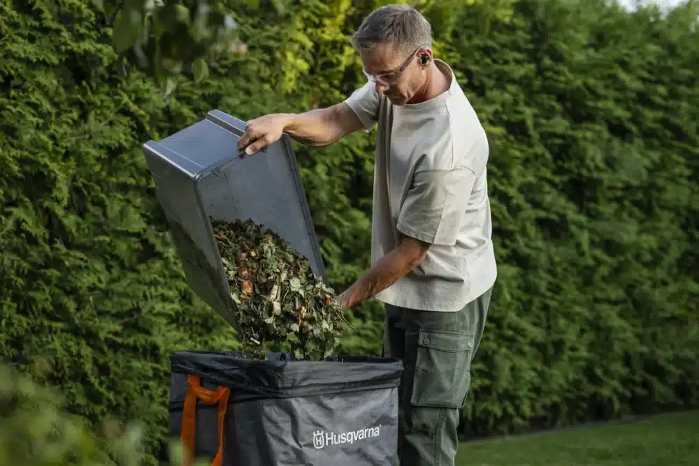 a man putting leaves into a trash can