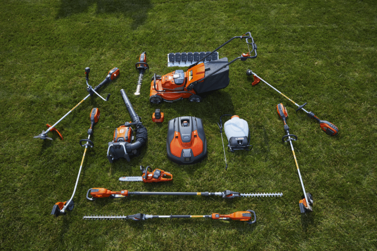Forskellige typer Husqvarna haveværktøjer opstillet på en græsplæne.