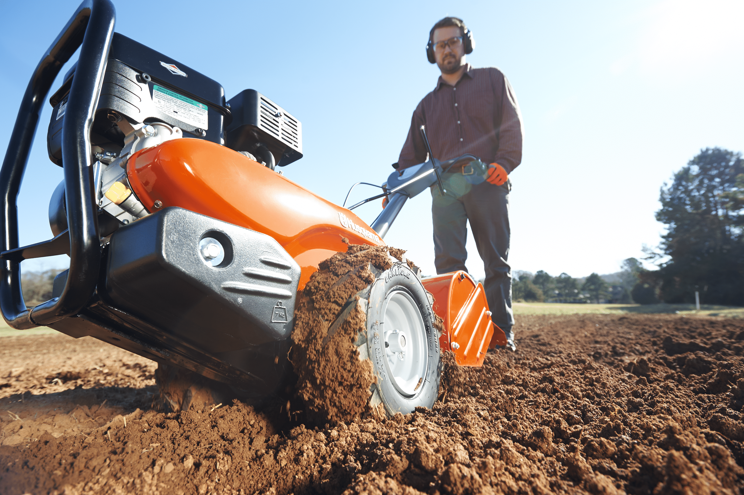 Mand styrer en jordfræser på en mark