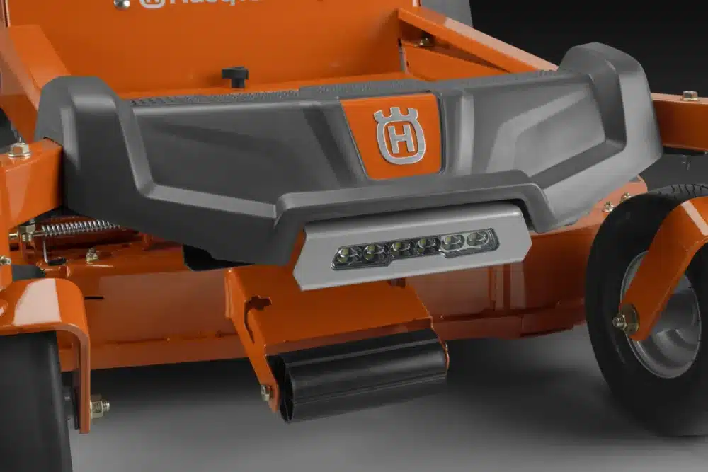 Nærbillede af Husqvarna plæneklippers forreste del med lys og hjul.