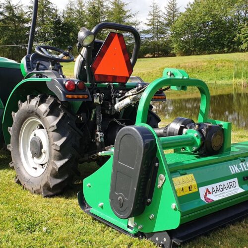 Traktor med tilkoblet maskine nær en sø