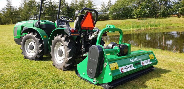 Traktor med tilkoblet maskine nær en sø