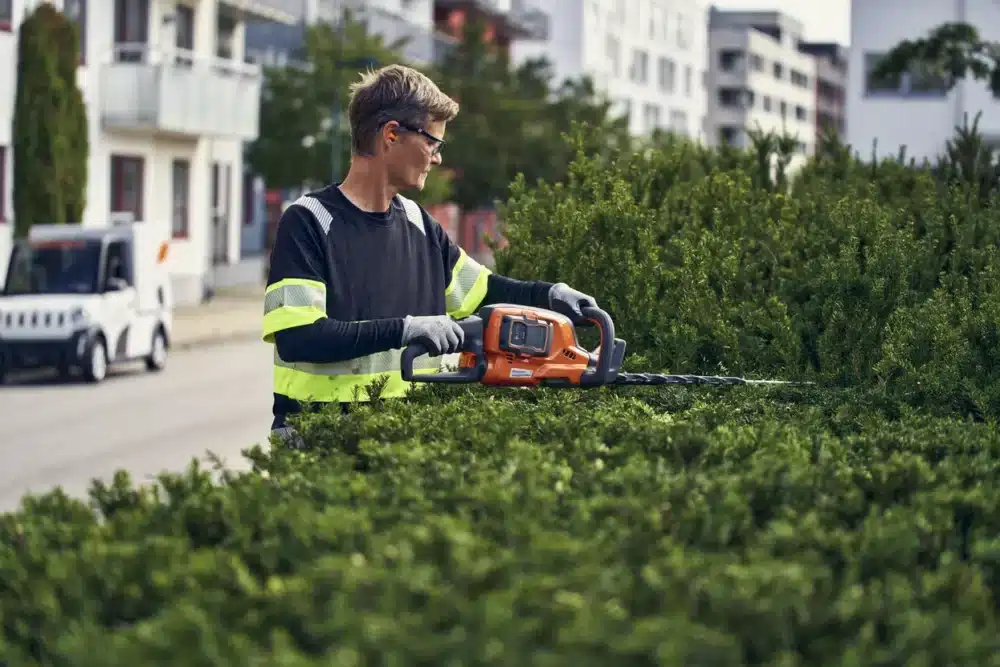 Mand med el-hækkeklipper klipper hæk