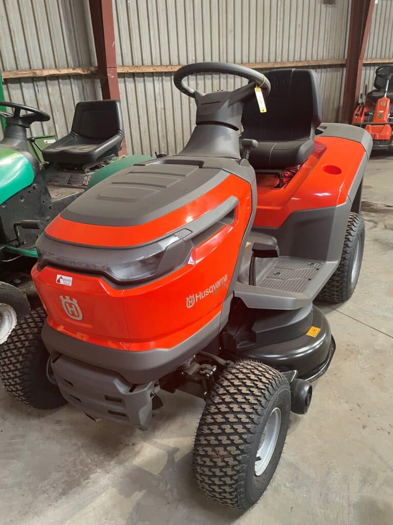 En rød Husqvarna plænetraktor står i en garage.
