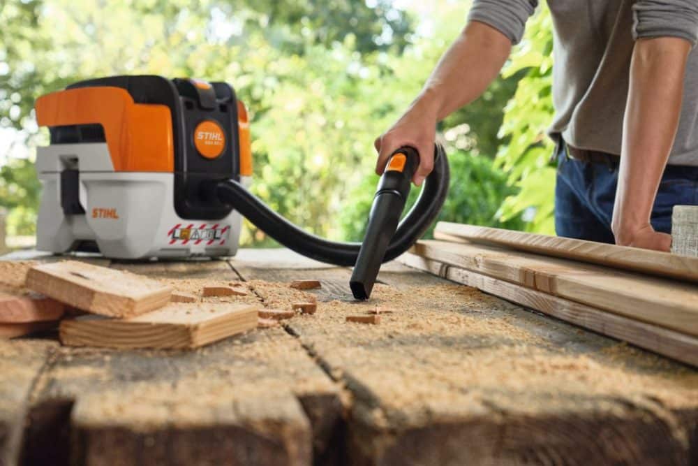Person støvsuger savsmuld med en STIHL støvsuger.