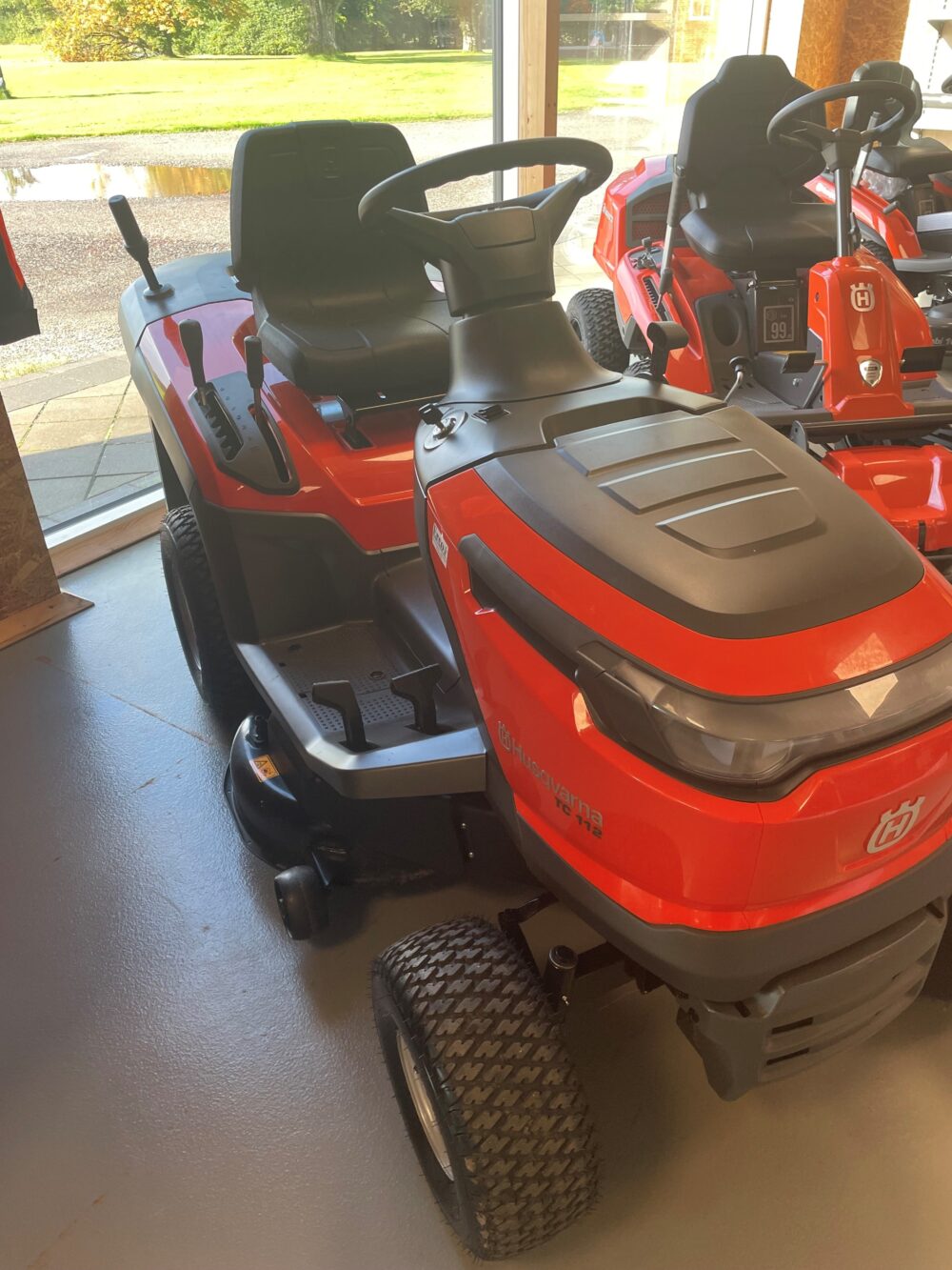 Rød plænetraktor indendørs ved et vindue