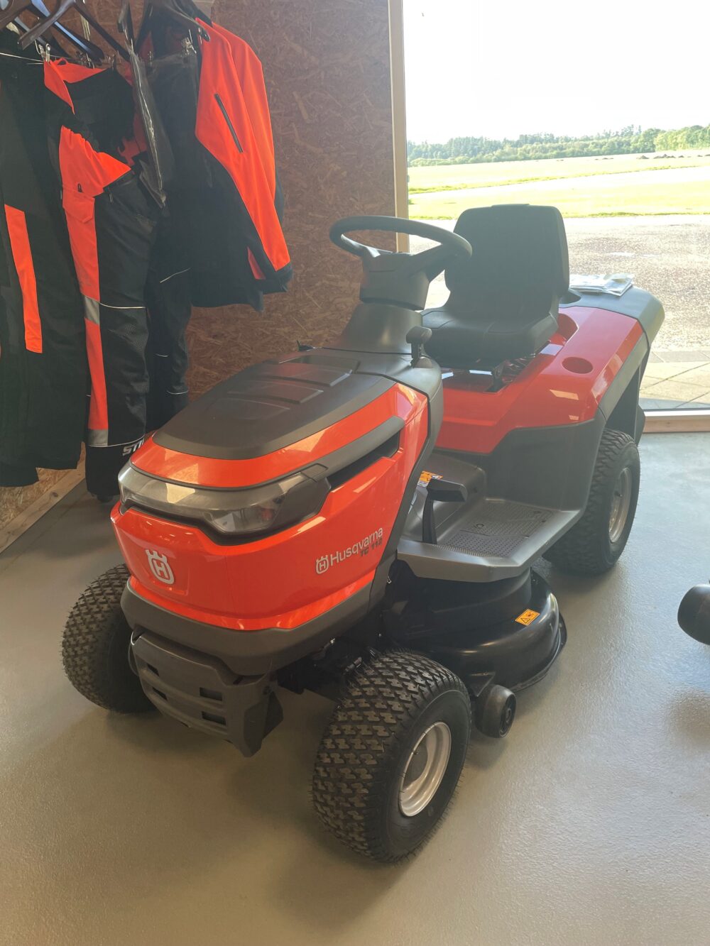 En orange Husqvarna havetraktor set indendørs.