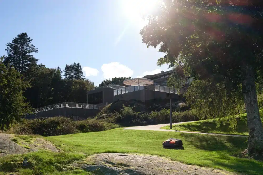 Robotplæneklipper på græsset nær en moderne bygning.