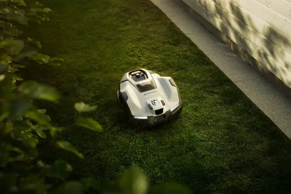 Robotplæneklipper på græsplæne nær en mur.