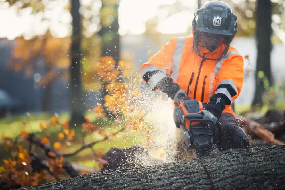 Person i orange arbejdstøj bruger en motorsav.