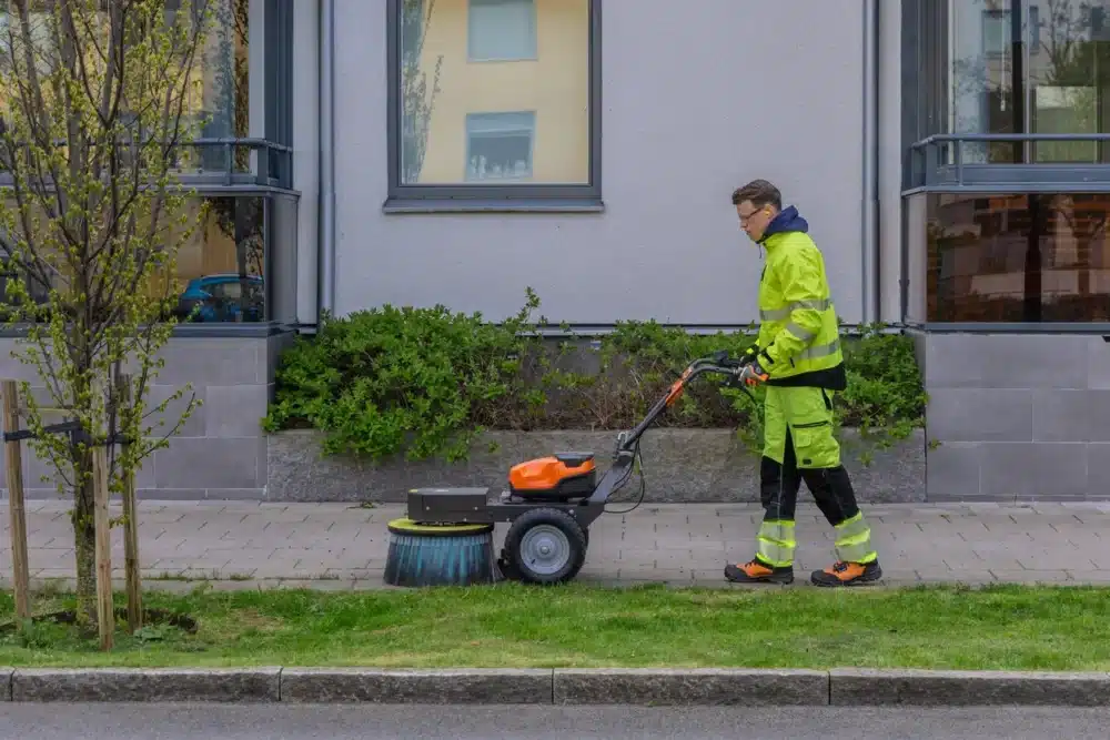 Person i refleksjakke bruger en fejemaskine.