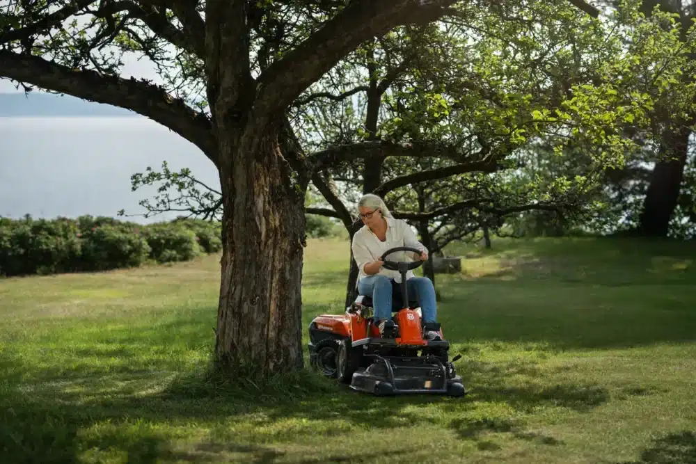 Person kører på en havetraktor under et træ nær vandet.