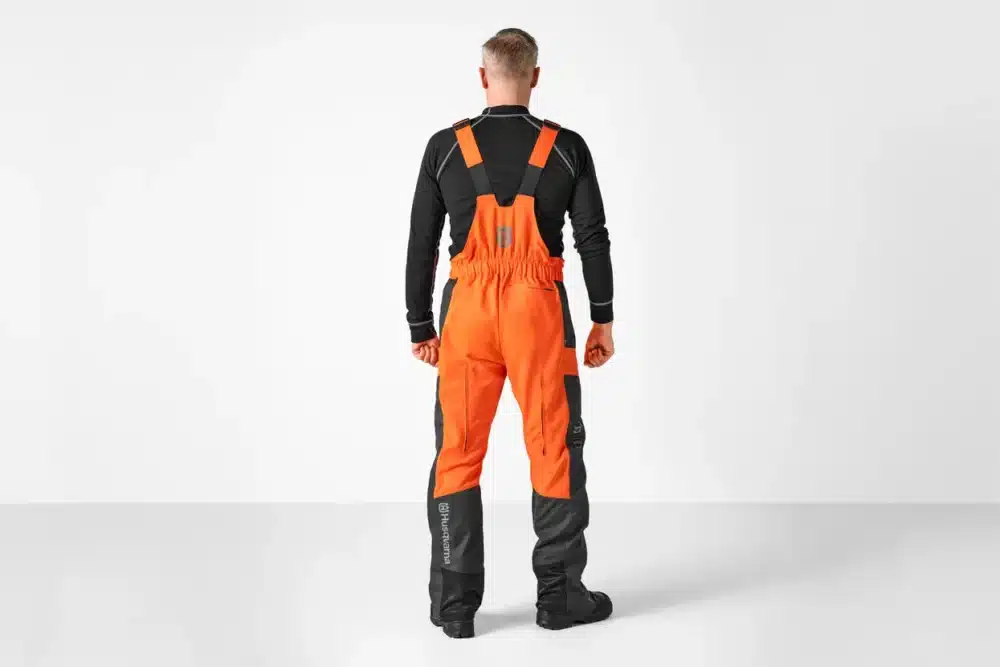 Person iført orange og sort arbejdstøj set bagfra.