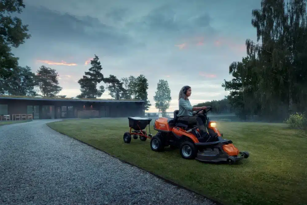 Kvinde på plænetraktor i duskregn