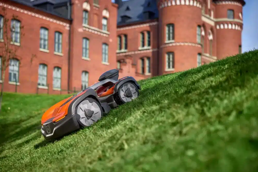 Robotplæneklipper på græsplæne foran et slot.