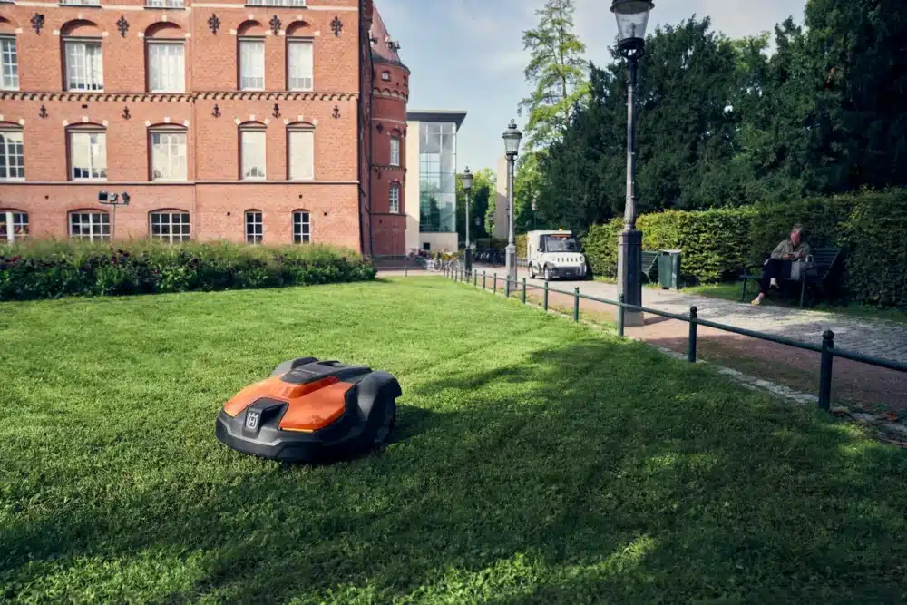 Robotplæneklipper på græs ved siden af en bygning