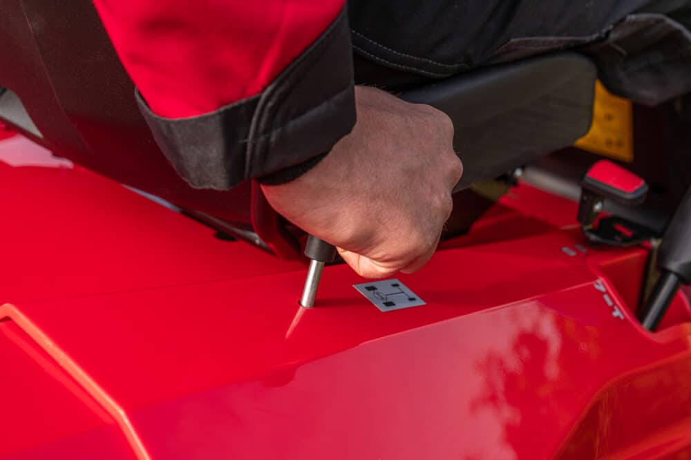 Hånd skifter gear på en rød maskine.